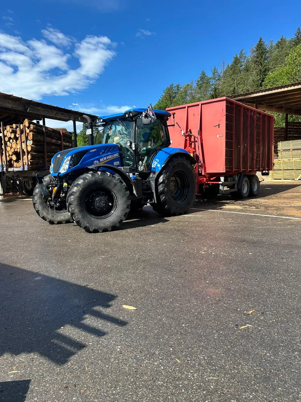 Traktor mit rotem Anhänger auf dem Hof